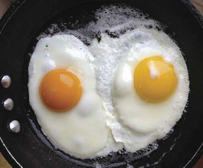 Two fried eggs, one with a yellow yolk, the other an orange yolk