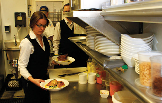 servers grab plates in the kitchen of Pain d'Avignon