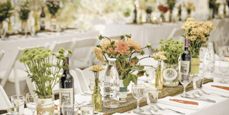 a beautiful table arrangement features fresh flowers, crystal glasses, and bottles of wine